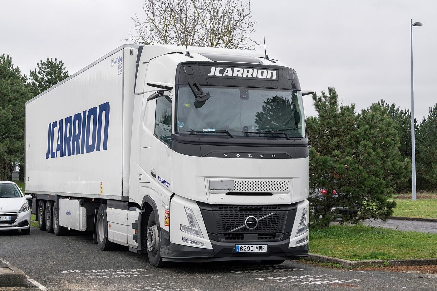 White Volvo FH Aero tractor unit with an extended rounded front end, coupled to a box semi-trailer
