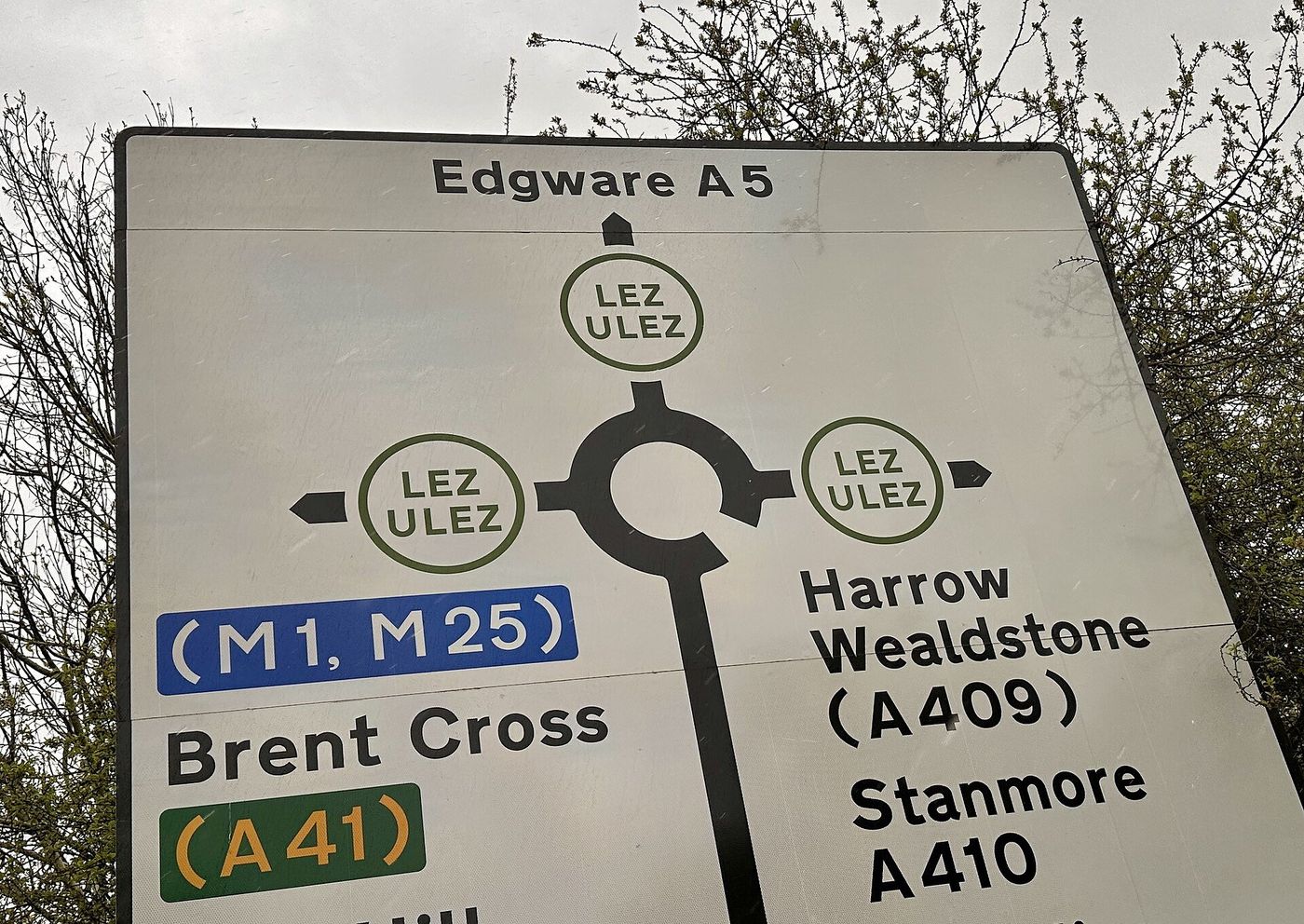 Roundabout direction sign in Harrow, north-west London, with a green LEZ and ULEZ roundel on each exit, towards Edgware (A5), Brent Cross (A41) for the M1 and M25, and Harrow, Wealdstone and Stanmore