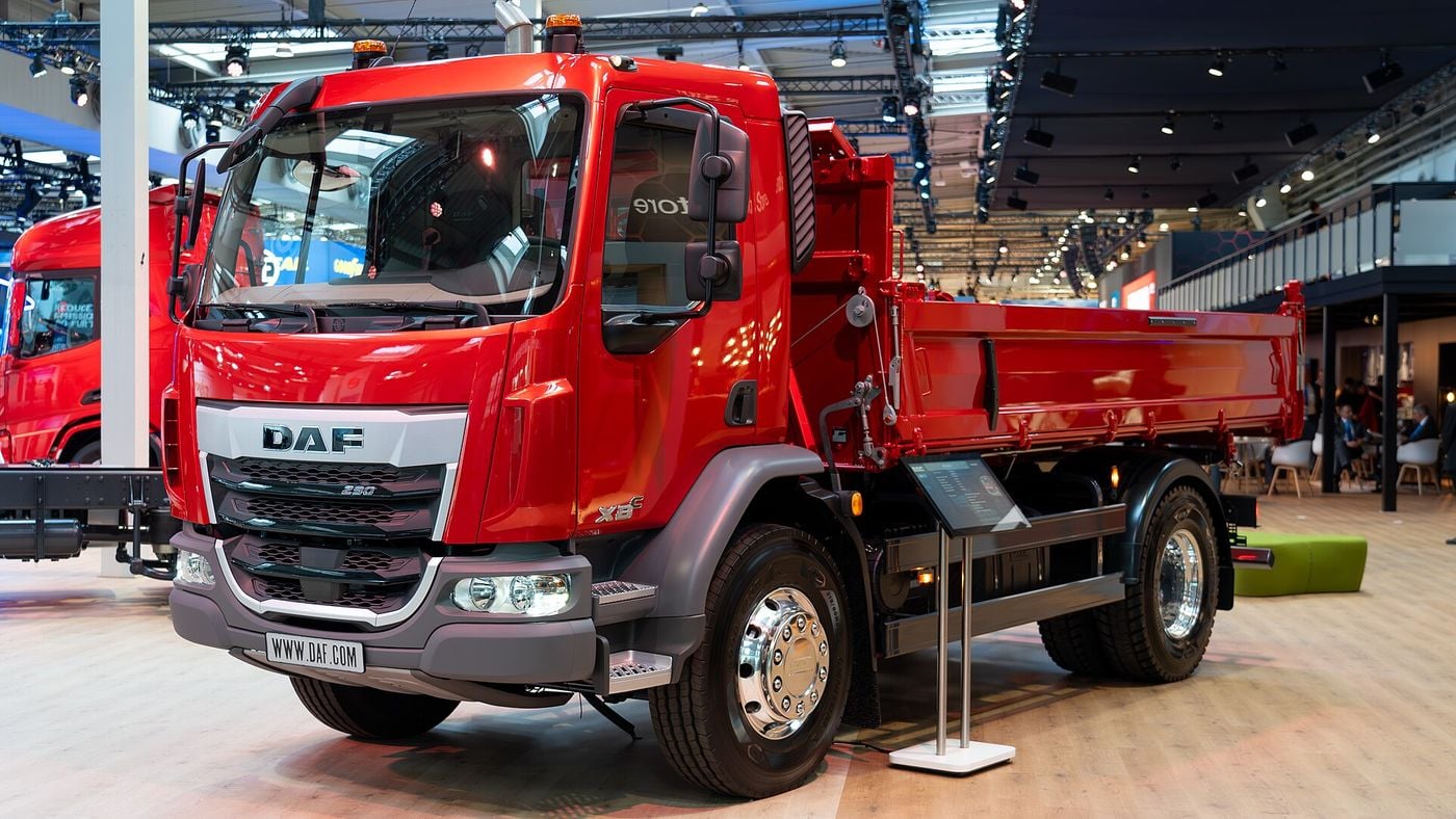 Red DAF XBC two-axle rigid with a tipper body, front three-quarter view on the DAF stand at IAA Transportation 2024 in Hanover, showing the New Generation cab and DAF grille