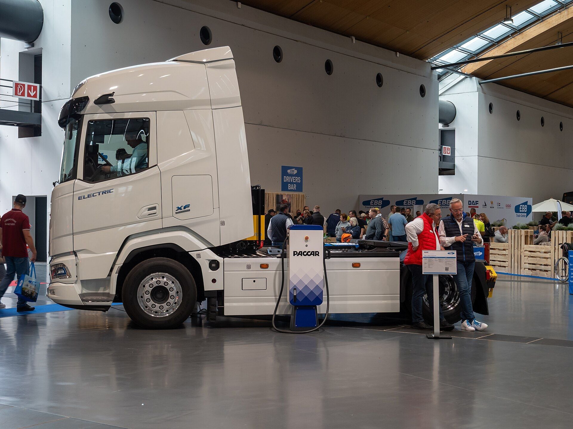 White DAF XF Electric two-axle tractor unit connected to a PACCAR charger on the show floor at Nufam 2025 in Rheinstetten