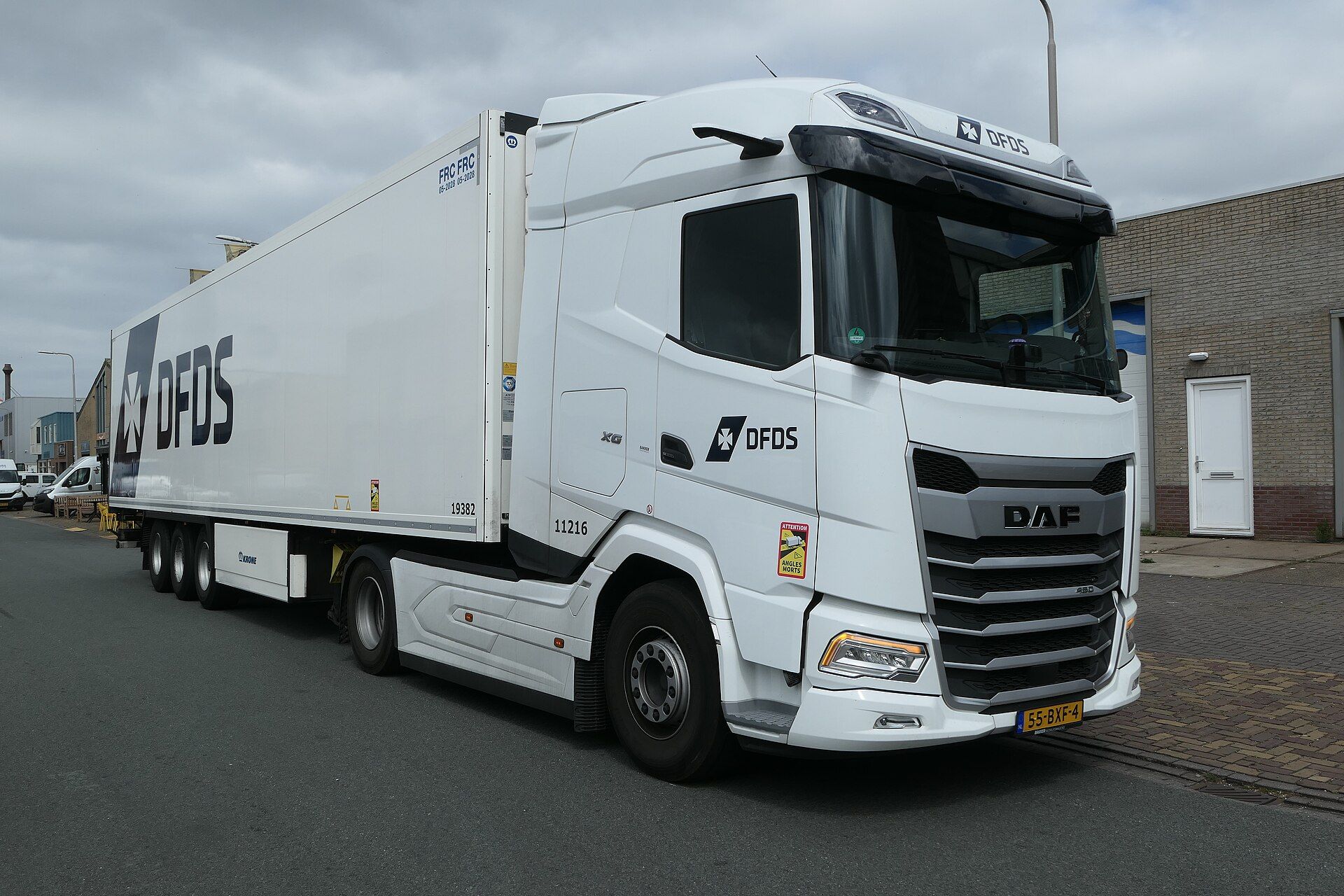 White DAF XG two-axle tractor unit with DFDS lettering, coupled to a three-axle Krone refrigerated semi-trailer and parked on a street