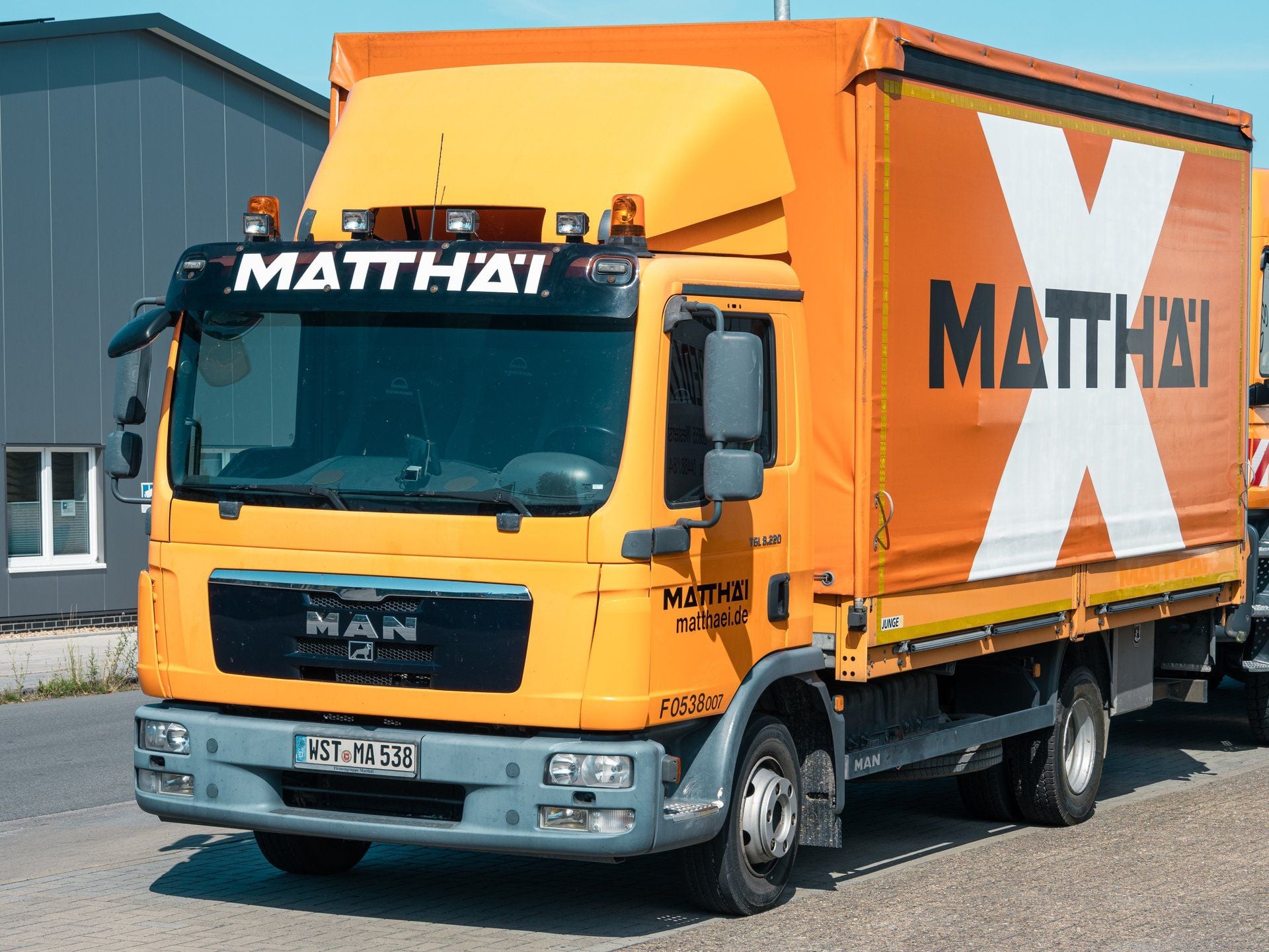 Zweiachsiger MAN TGL 8.220 mit orangefarbenem Fahrerhaus und Planenaufbau auf einem Betriebsgelände in Westerstede