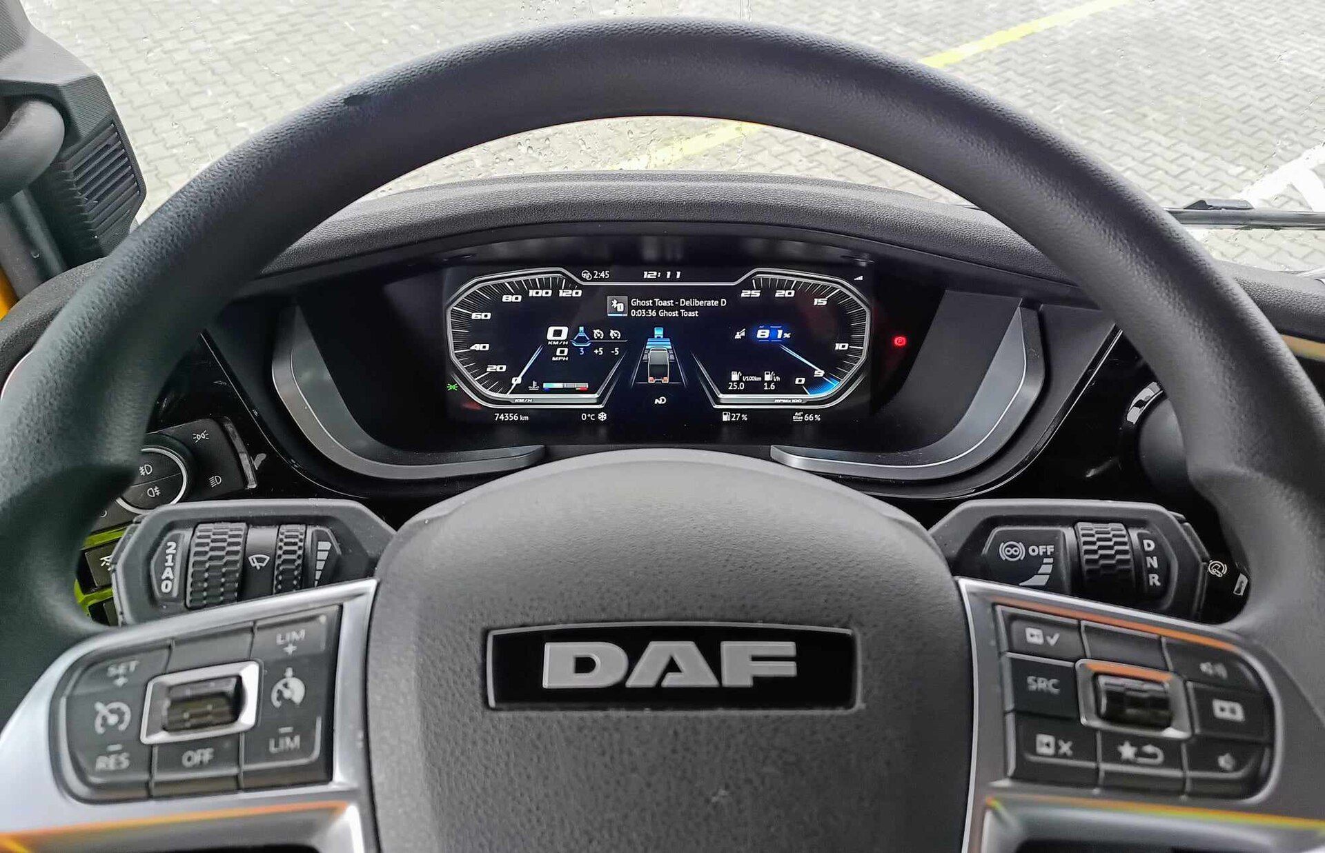 Fully digital instrument display of a DAF tractor seen through the steering wheel, with cruise and speed-limiter switches on the wheel spokes