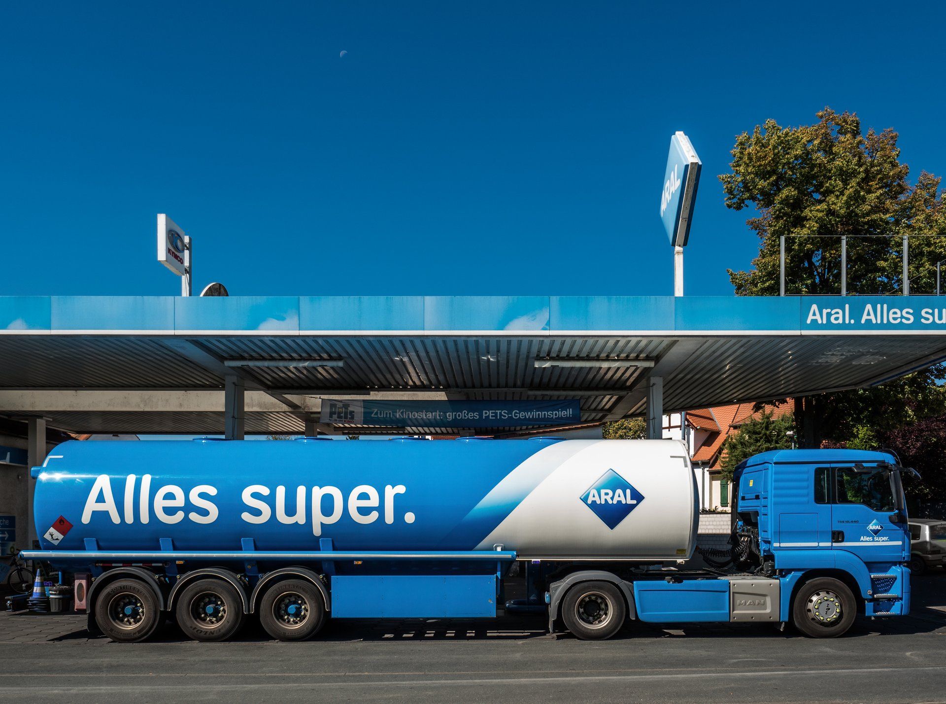 Blue road fuel tanker semi-trailer parked in front of a petrol station canopy in Bamberg, Germany