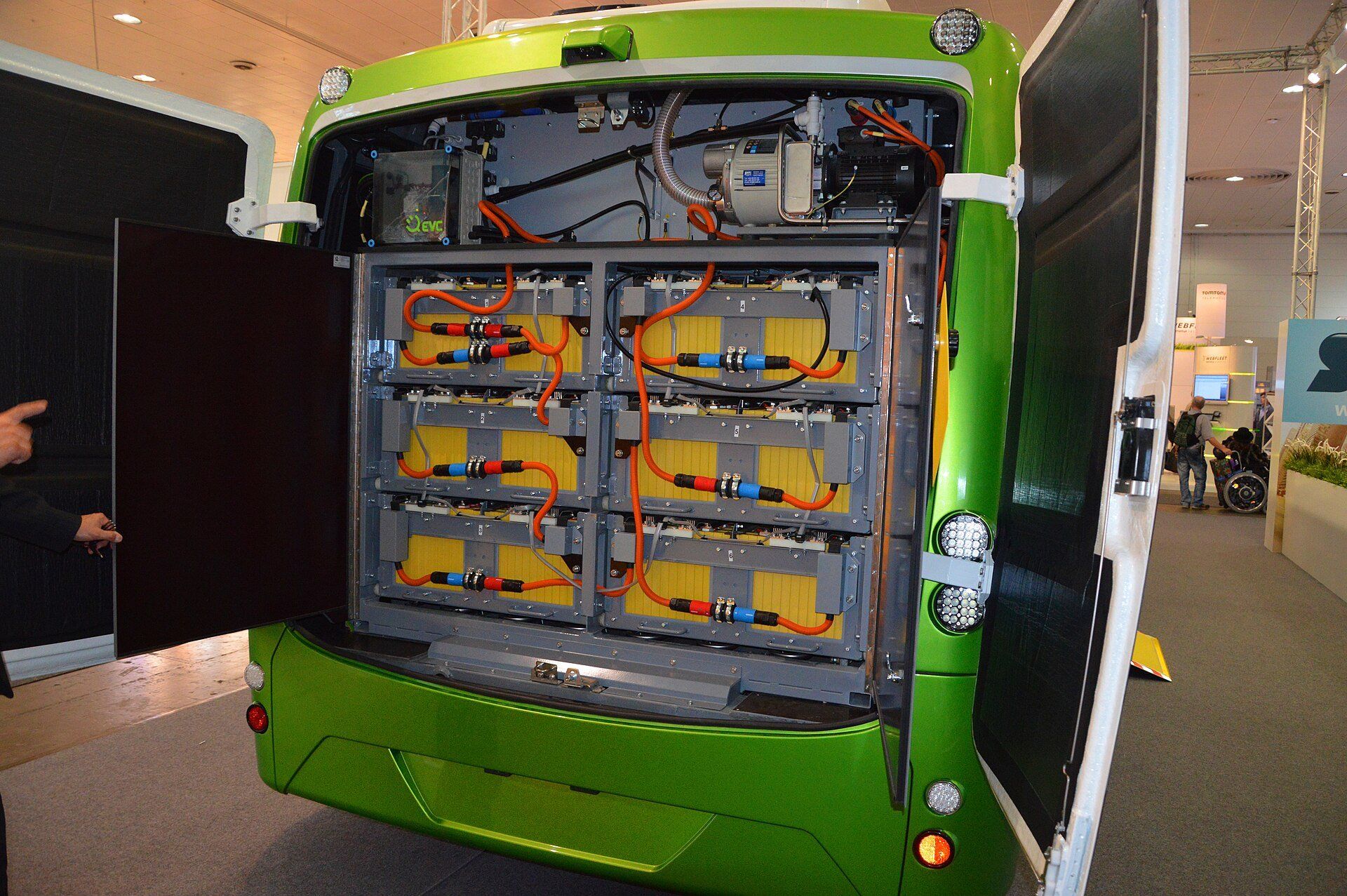 Open rear battery compartment of an SOR EBN 11 electric city bus showing the traction lithium-ion battery modules and orange high-voltage cables, IAA 2014 in Hanover