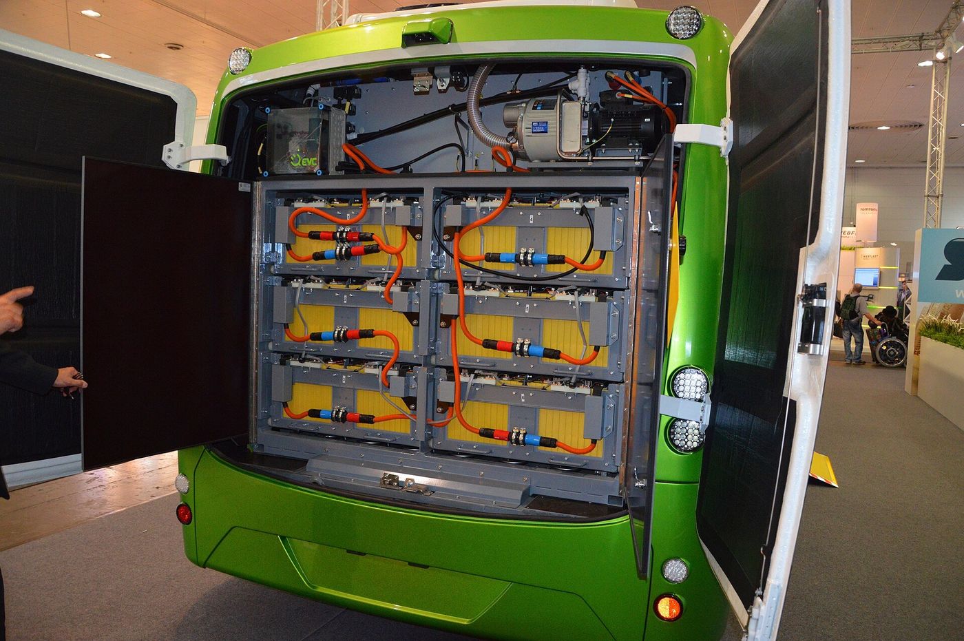 Open rear battery compartment of an SOR EBN 11 electric city bus showing the traction lithium-ion battery modules and orange high-voltage cables, IAA 2014 in Hanover
