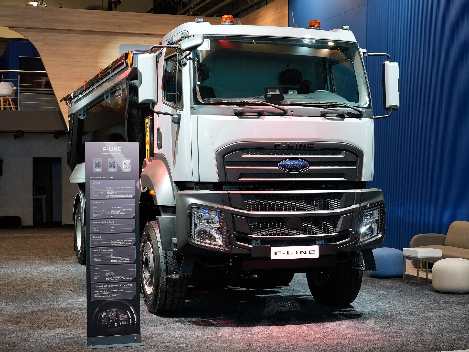 White Ford F-LINE 4445XD tipper seen from the front, with a day cab, two amber roof beacons and an information board beside it, at IAA Transportation 2026