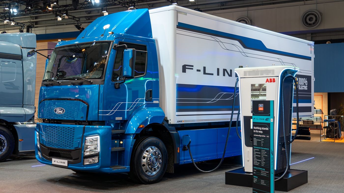 Blue Ford Trucks F-LINE E electric truck with a box body, connected to a charger at the Ford Trucks stand at IAA Transportation 2024