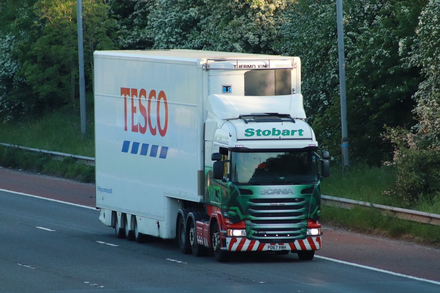 Scania R450 tractor unit pulling a white double-deck refrigerated semi-trailer on the M6 motorway in England