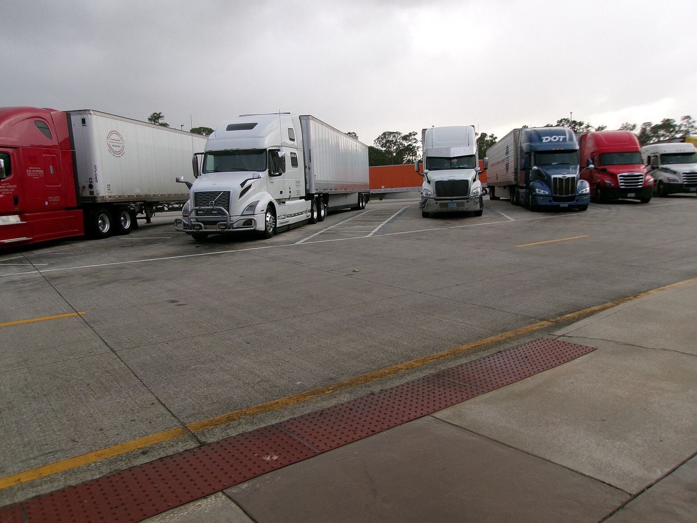 Tractor-trailers from several makers parked side by side in the truck parking area of a southbound Interstate 95 rest area in Martin County, Florida