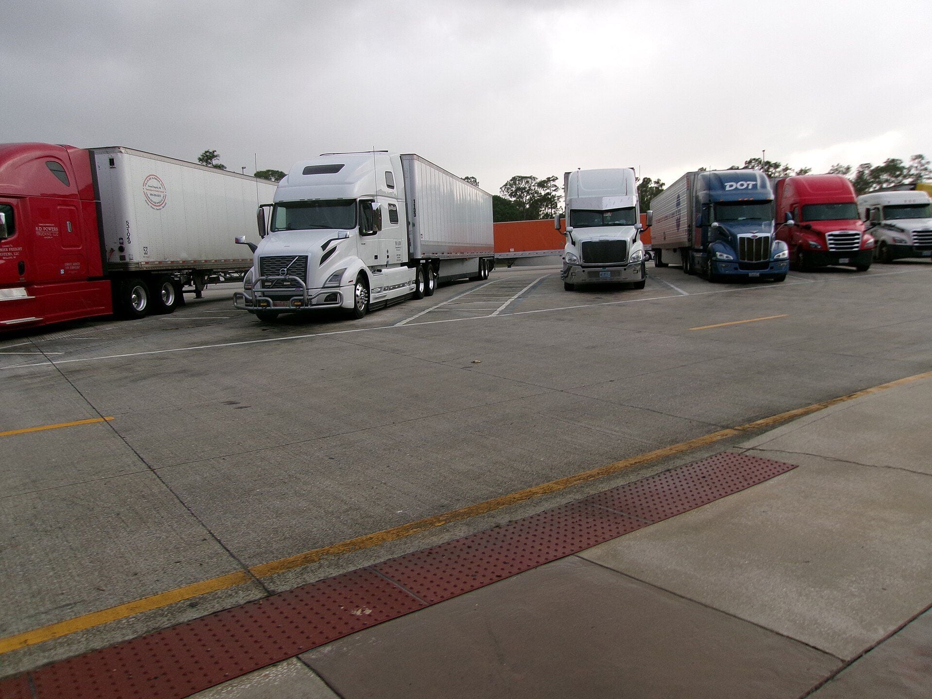 Tractor-trailers from several makers parked side by side in the truck parking area of a southbound Interstate 95 rest area in Martin County, Florida