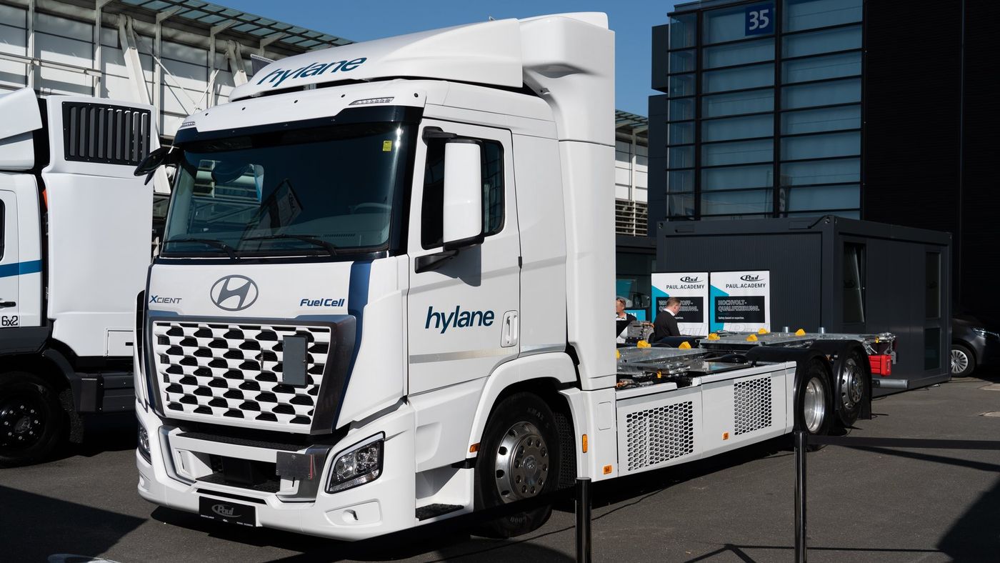 A white Hyundai XCIENT Fuel Cell 6x2 chassis cab seen from the front and side on a trade-fair site, with the Hyundai logo and the XCIENT Fuel Cell badges on the front