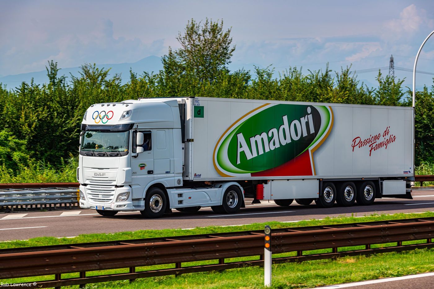Trattore stradale DAF XF bianco con semirimorchio frigorifero Amadori su un'autostrada tra Modena e Verona; sul frontale del semirimorchio, sotto la sigla «FRC», il cartello verde quadrato con la lettera «d»; in primo piano un guard-rail