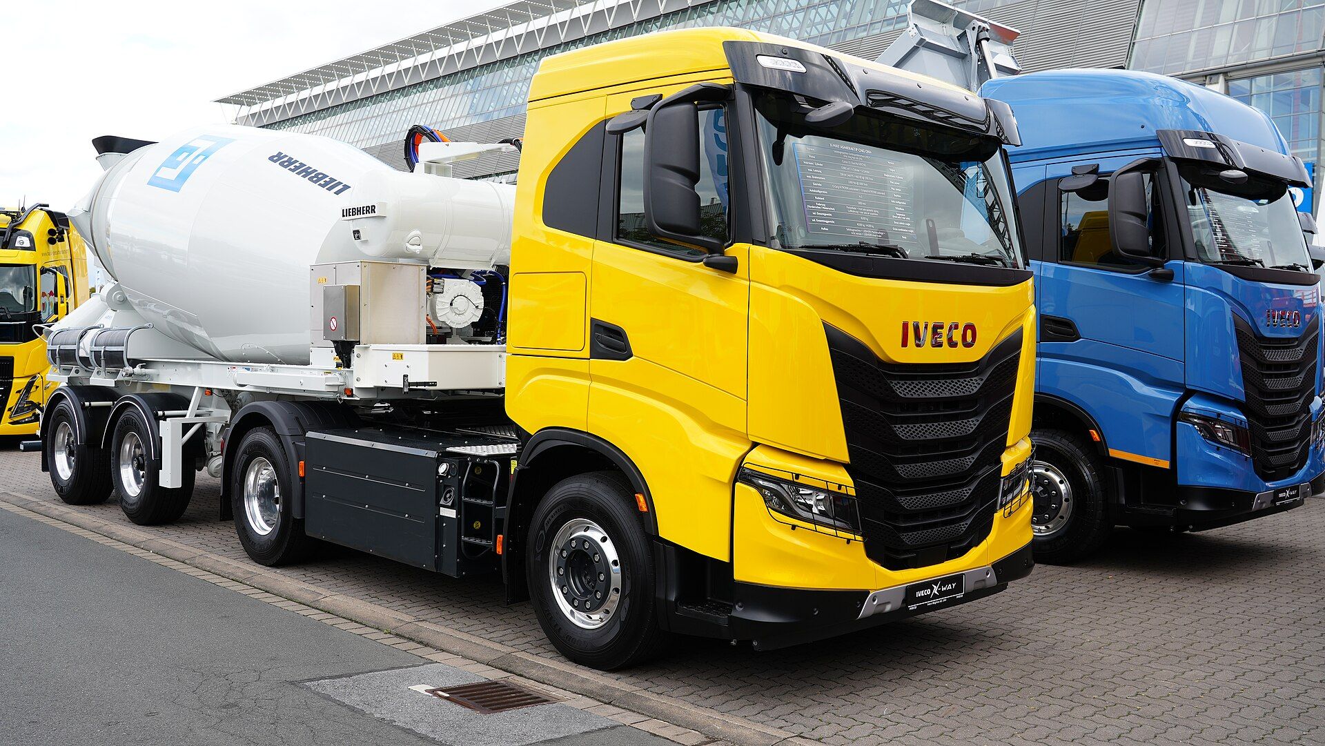 Yellow Iveco X-Way natural-gas 4x2 tractor unit with the full-width AS cab, coupled to a Liebherr concrete-mixer semi-trailer, at IAA Transportation 2022 in Hanover