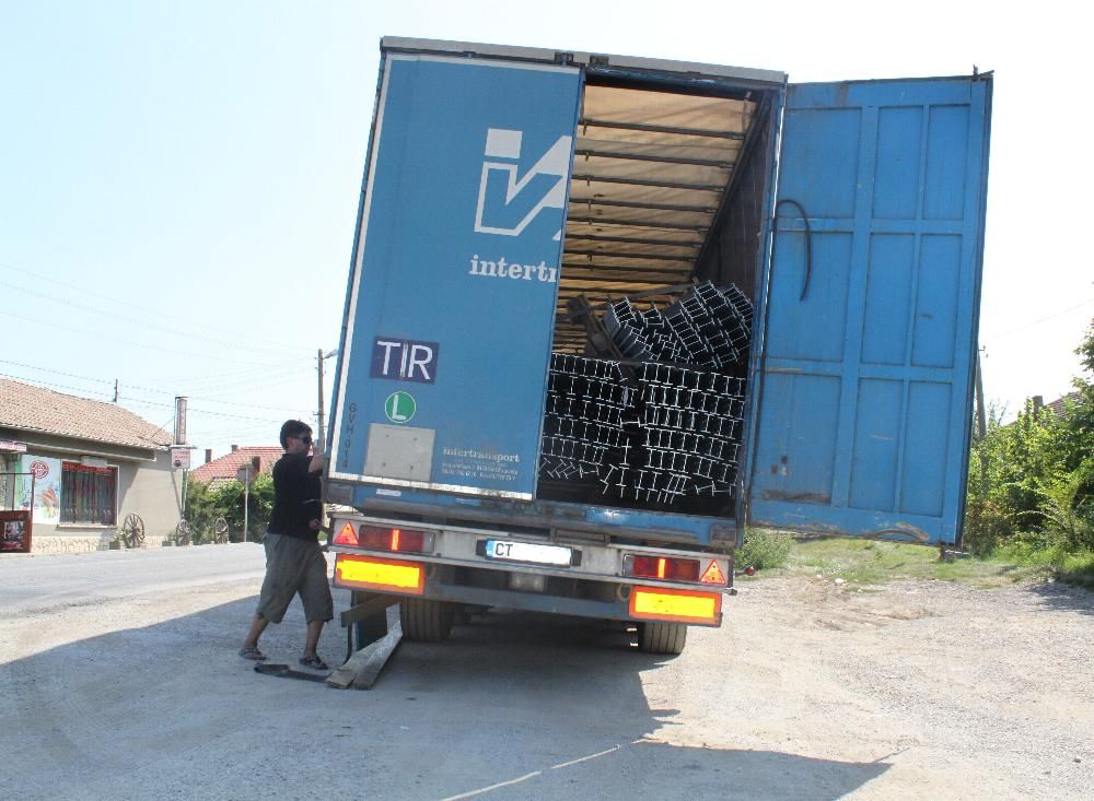 Steel profiles slumped out of position inside the open rear of a trailer at the roadside