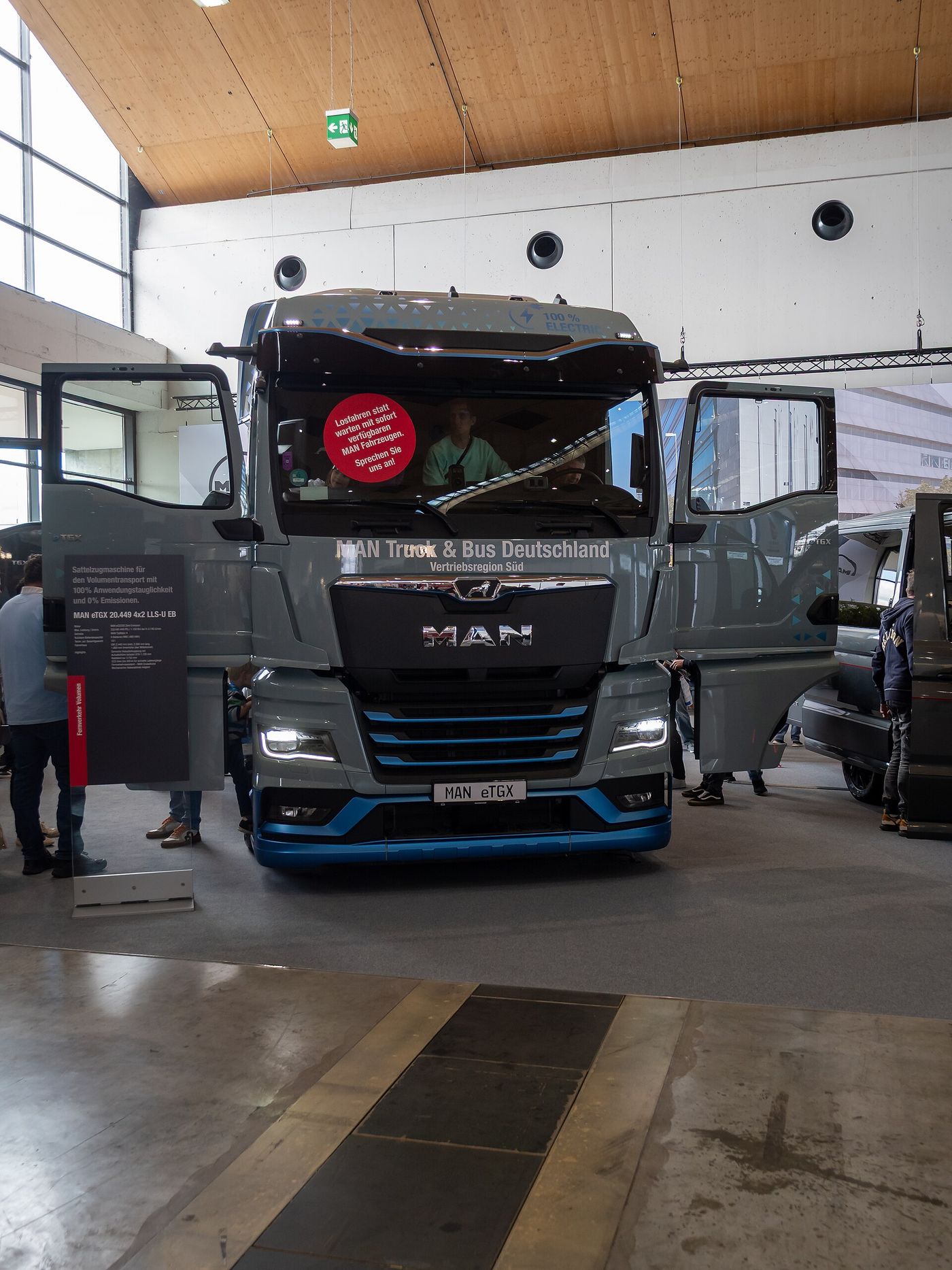 Grey MAN eTGX 20.449 4x2 electric semitrailer tractor seen head-on with both cab doors open on a stand at Nufam 2025 in Rheinstetten