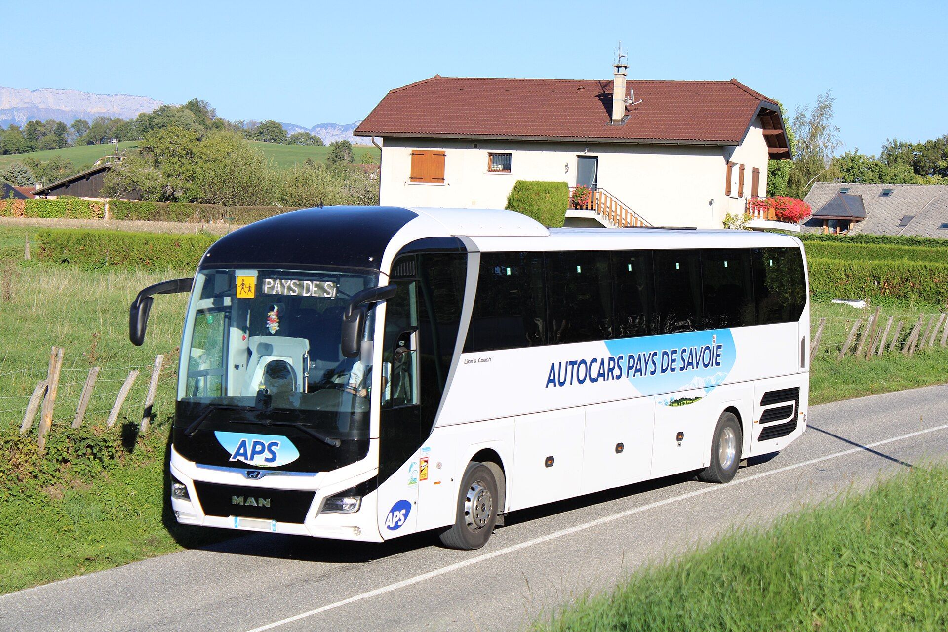 Weißer MAN-Reisebus in der Lackierung von Autocars Pays de Savoie auf einer Landstraße bei Marcellaz-Albanais, Frankreich, mit dem Lion's-Coach-Modellschriftzug an der Flanke