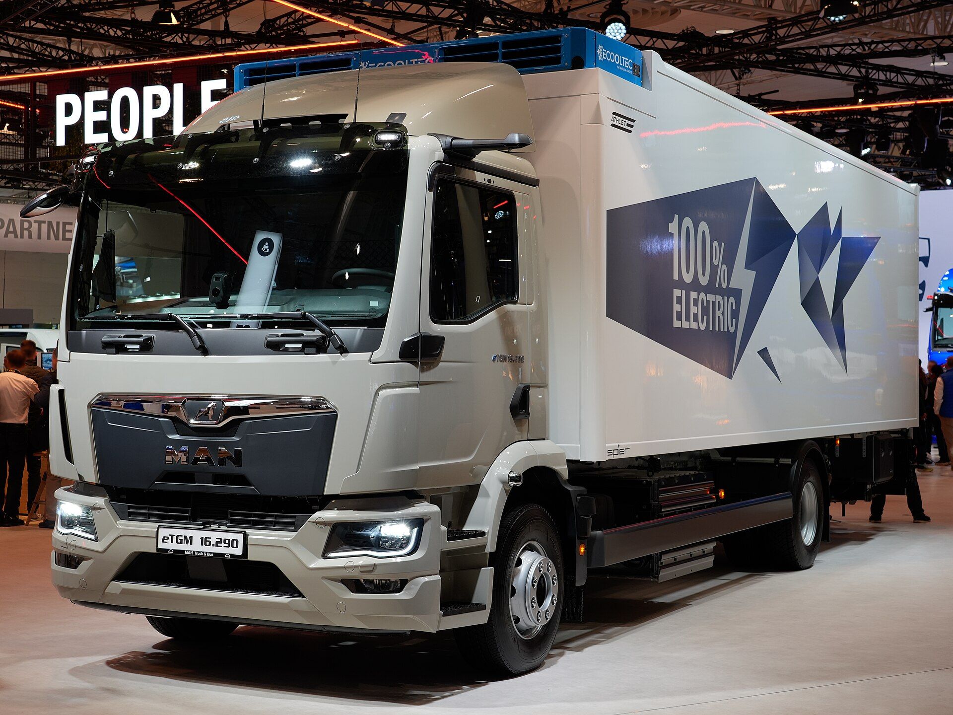 White battery-electric MAN eTGM two-axle rigid with a box body marked 100% Electric and a refrigeration unit above the cab, on MAN's stand at IAA Transportation 2026