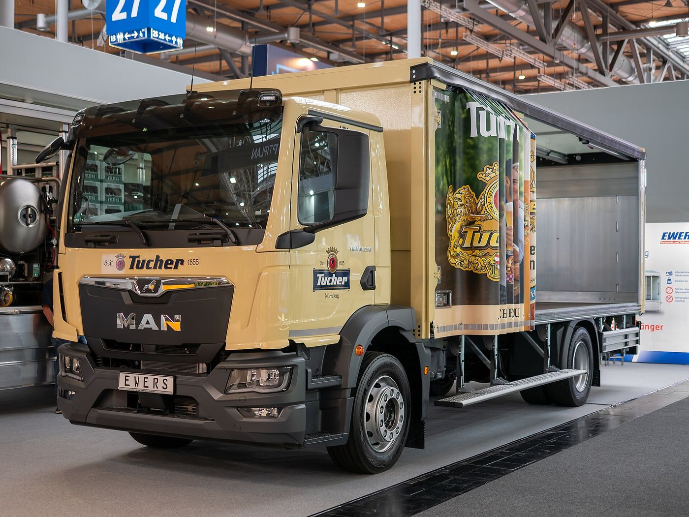 Beige MAN TGM 18.250 two-axle rigid with a short cab and a brewery's beverage body with its side open, on a stand at IAA Transportation 2026 in Hanover