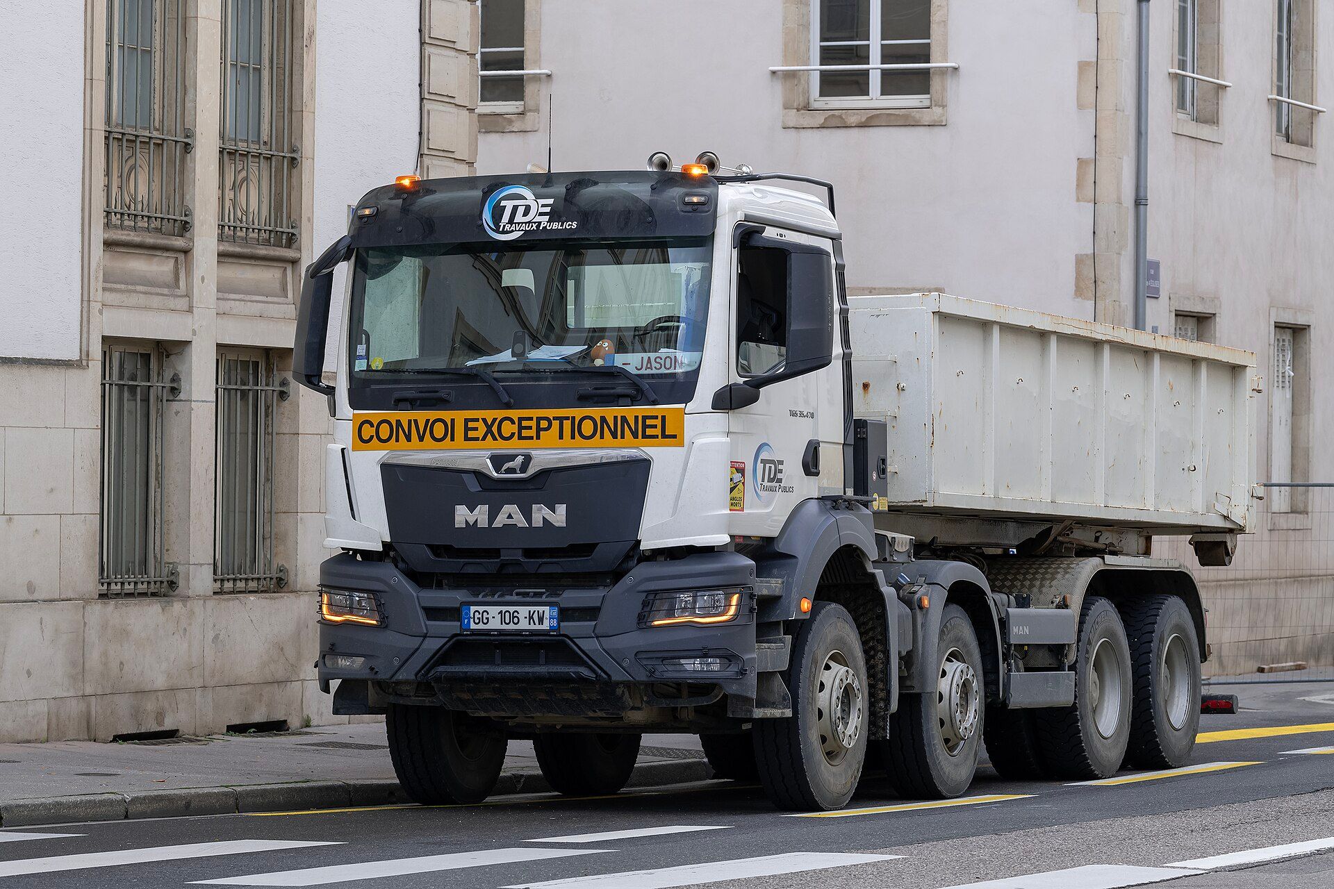 White four-axle MAN TGS 35.470 tipper with a steel body, parked at the kerb in a French street in public-works livery