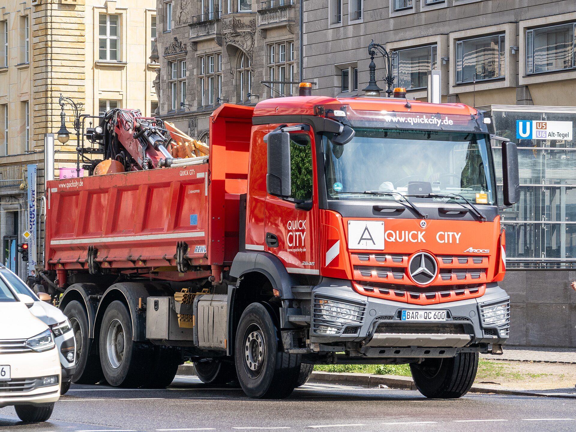 Red Mercedes-Benz Arocs 2646 three-axle tipper with a loading crane folded behind the cab, in Berlin street traffic