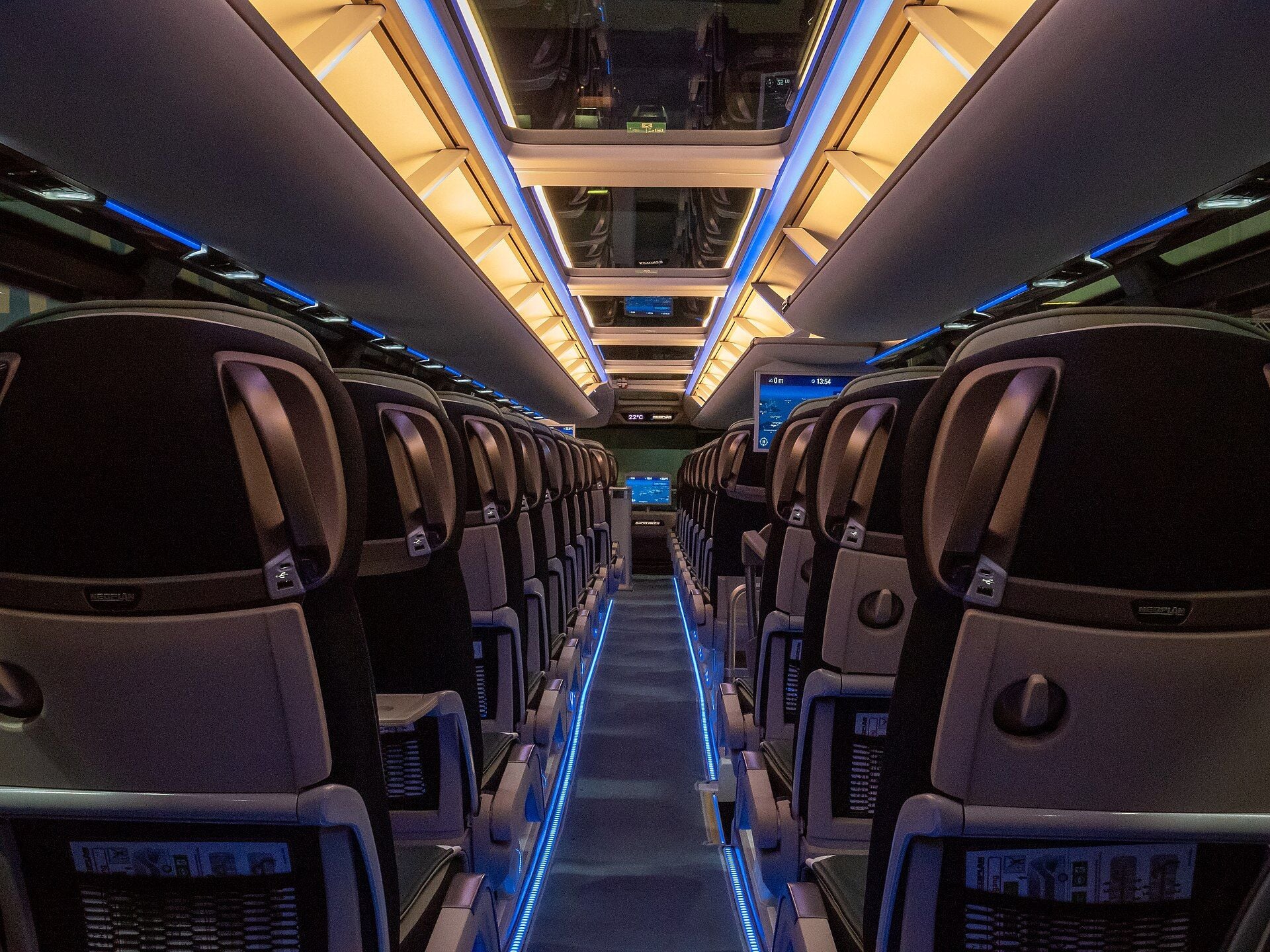 Upper deck of the Neoplan Skyliner Auwärter Edition: rows of dark coach seats with seat-back screens, glazed roof panels and blue aisle lighting