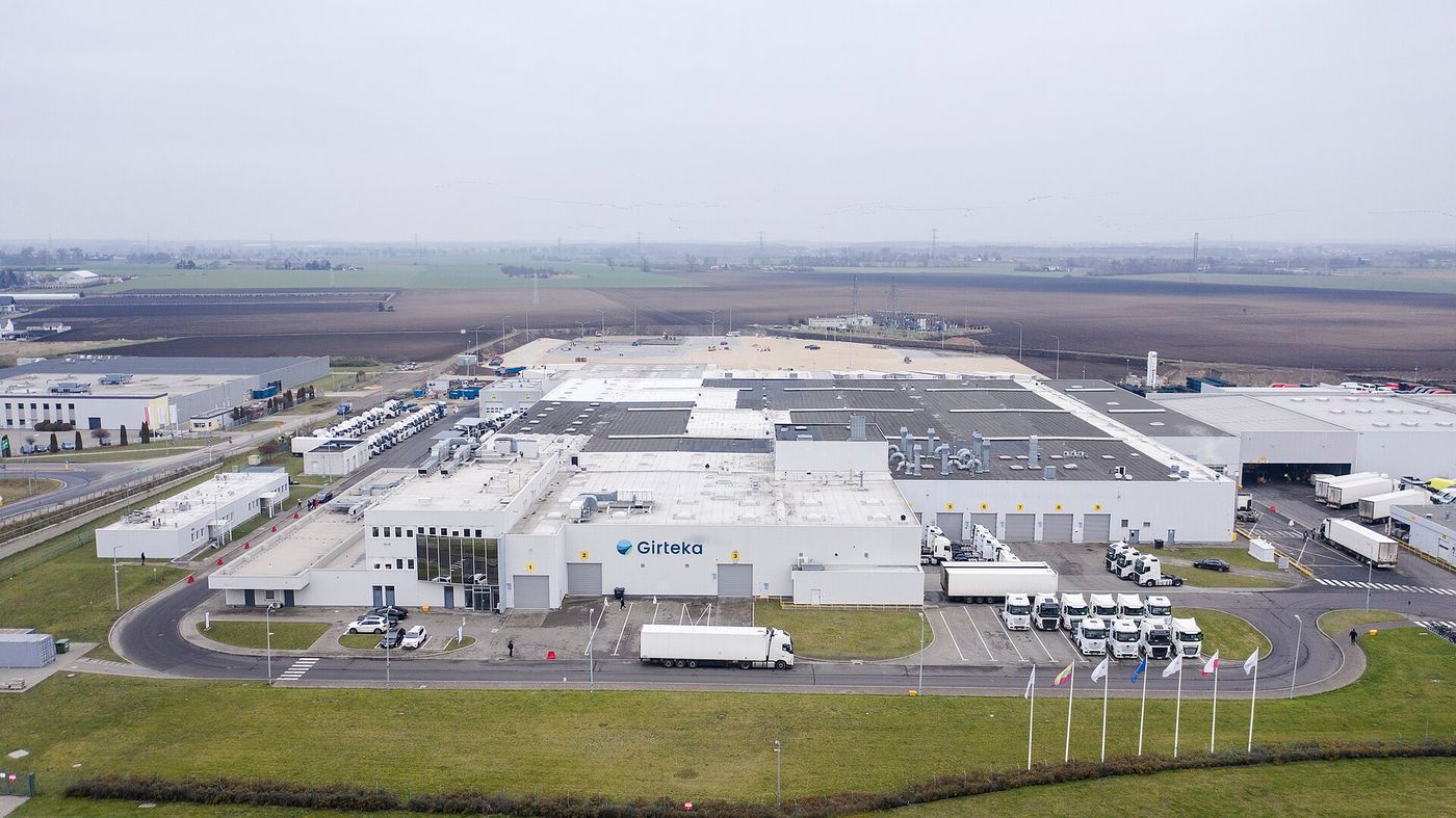 Vue aérienne de la base d'un transporteur routier de marchandises en Pologne, avec des tracteurs routiers et des semi-remorques stationnés à côté de l'entrepôt
