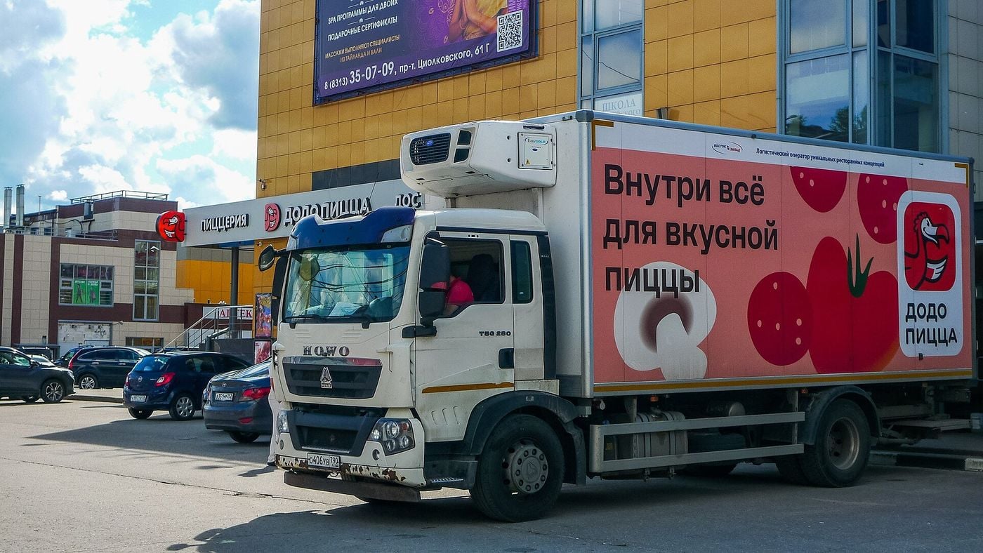 Рефрижераторный грузовик HOWO T5G с фургоном логистического оператора у торгового центра в Дзержинске, за рулём водитель
