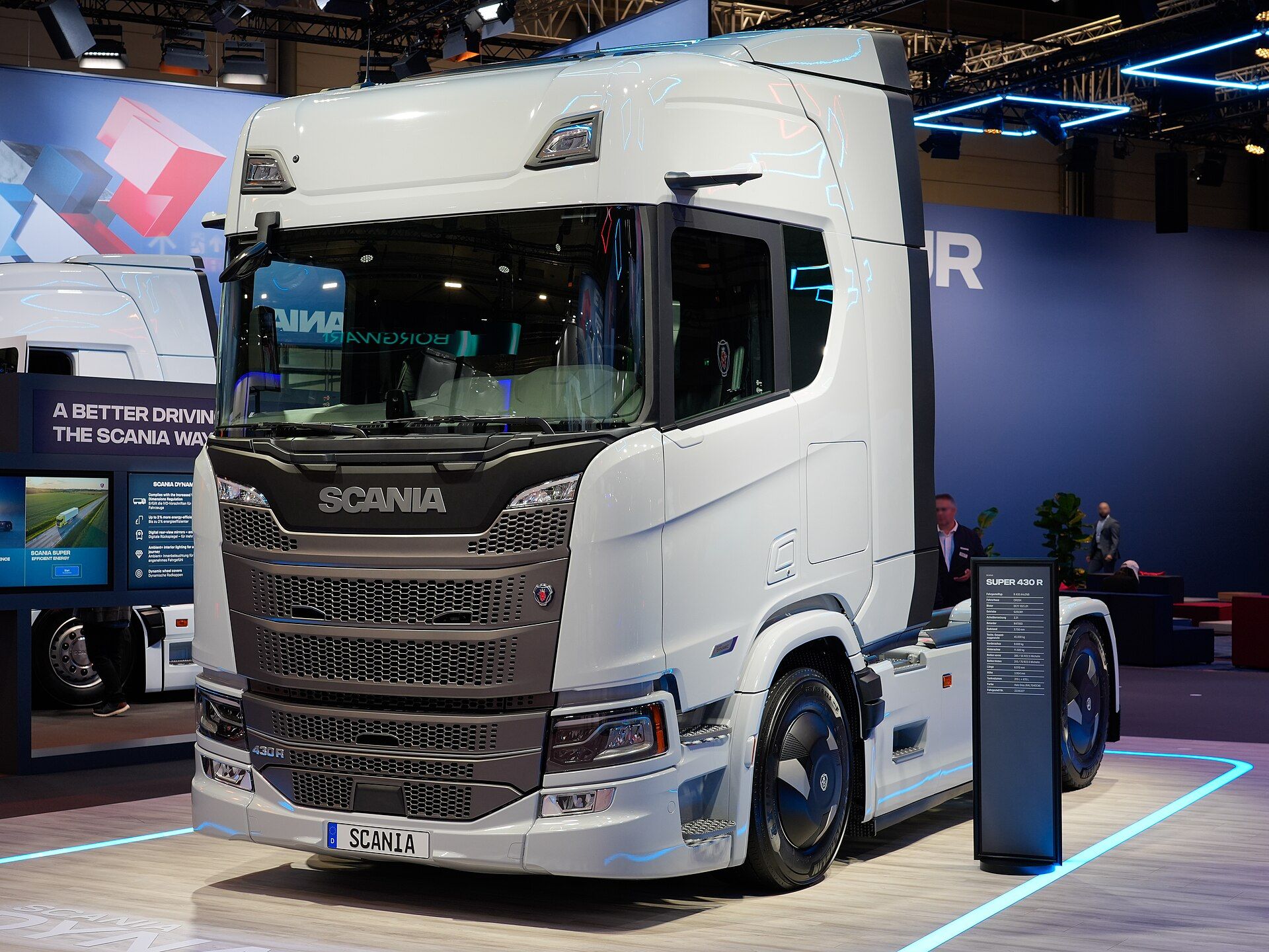 Light grey Scania Super 430 R two-axle tractor unit with the redesigned front, slim camera arms instead of large exterior mirrors and covered wheels, on Scania's stand at IAA Transportation 2026