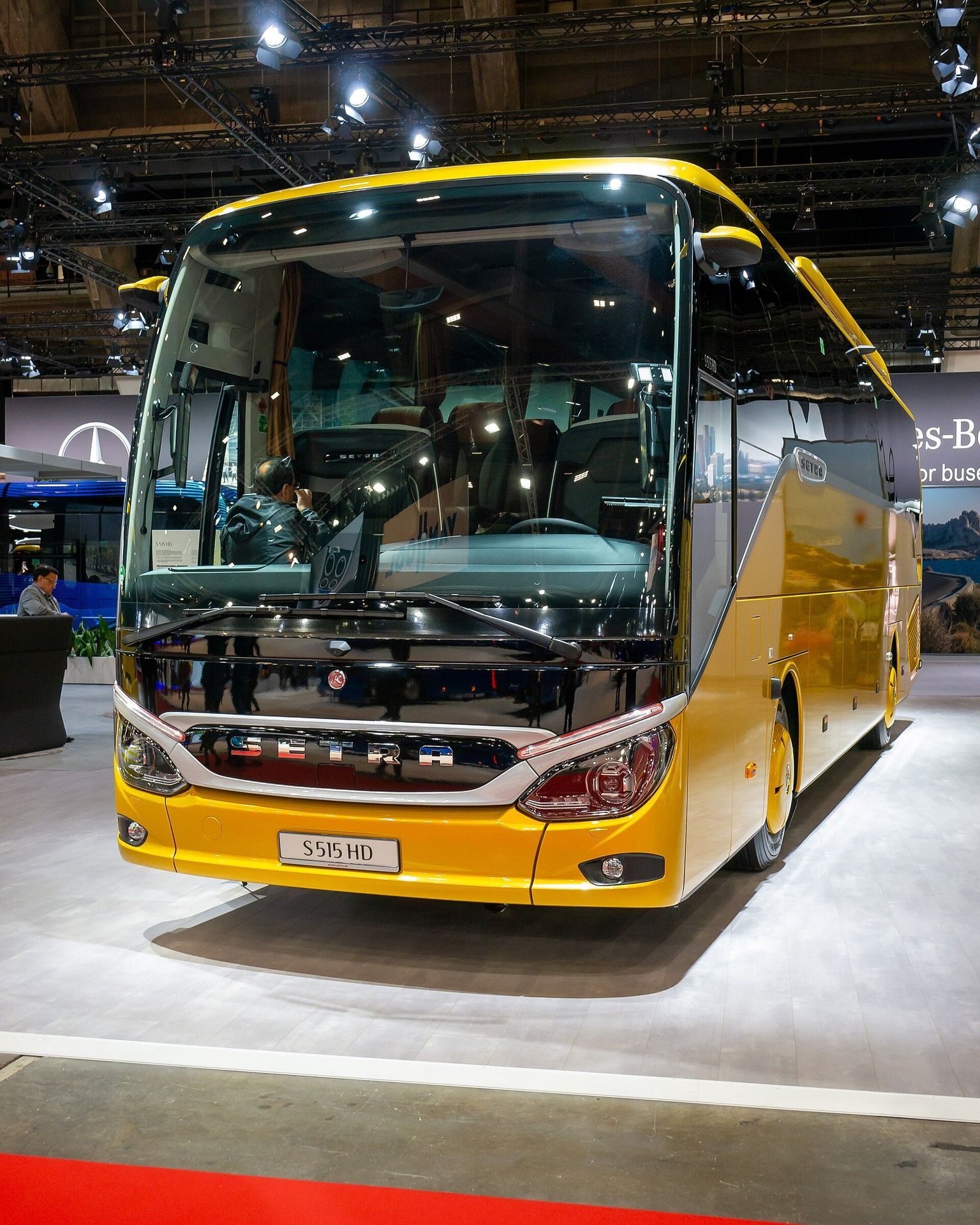 Yellow Setra ComfortClass S 515 HD seen from the front at Busworld Europe 2023 in Brussels, showing the black front panel with chrome SETRA lettering, the silver trim and the S 515 HD plate