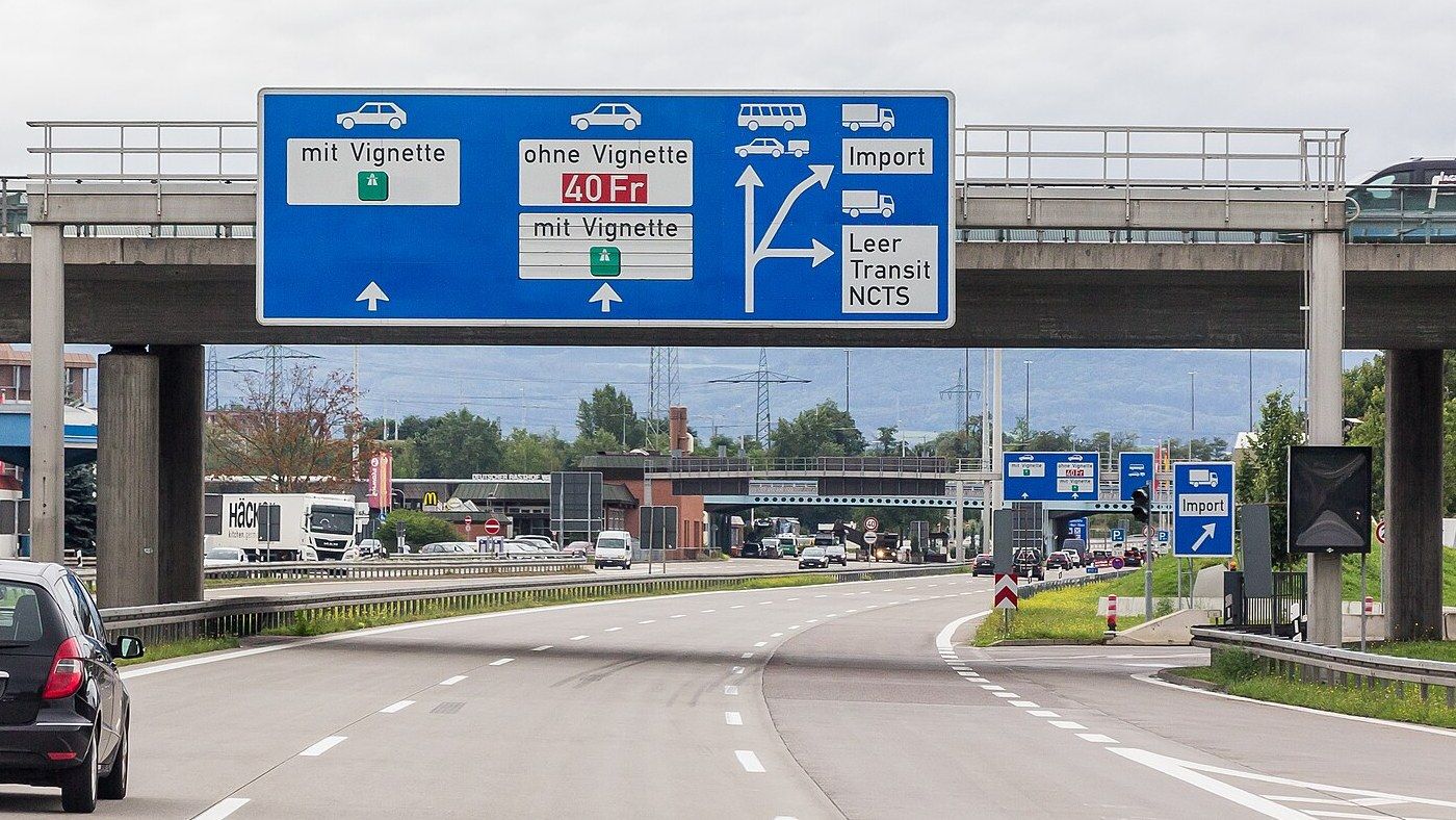 Overhead sign on the A 5 motorway at the German-Swiss border crossing at Weil am Rhein, sending cars with or without a vignette straight on and lorries to the right into lanes marked Import and Leer Transit NCTS