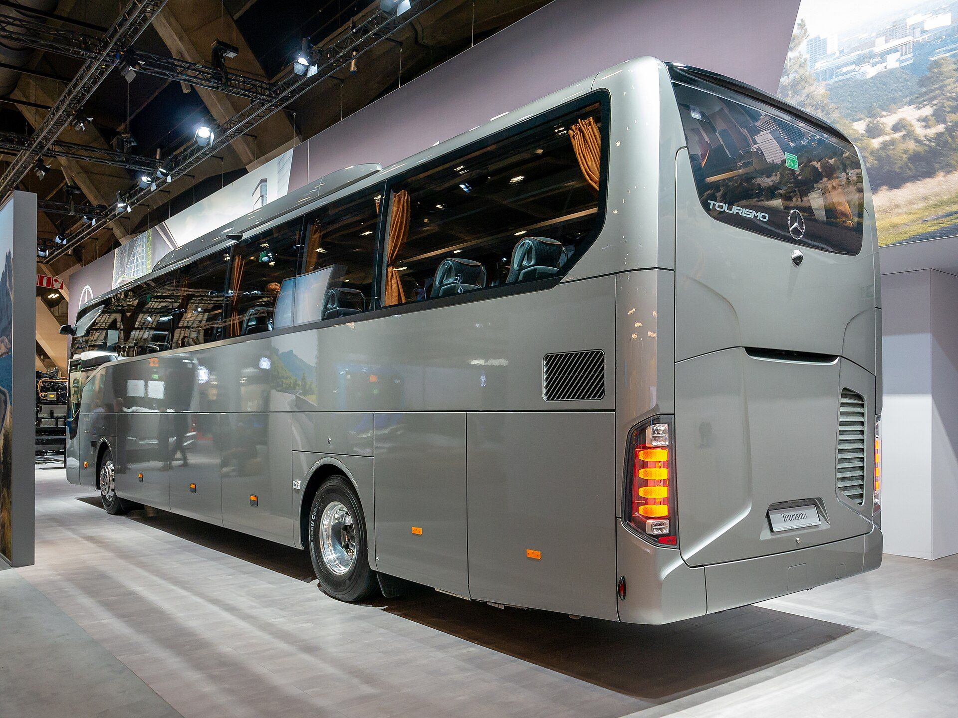 Silberner Mercedes-Benz Tourismo M/2, ein Hochdecker-Reisebus, auf einem Messestand, von der Heckdiagonale gesehen