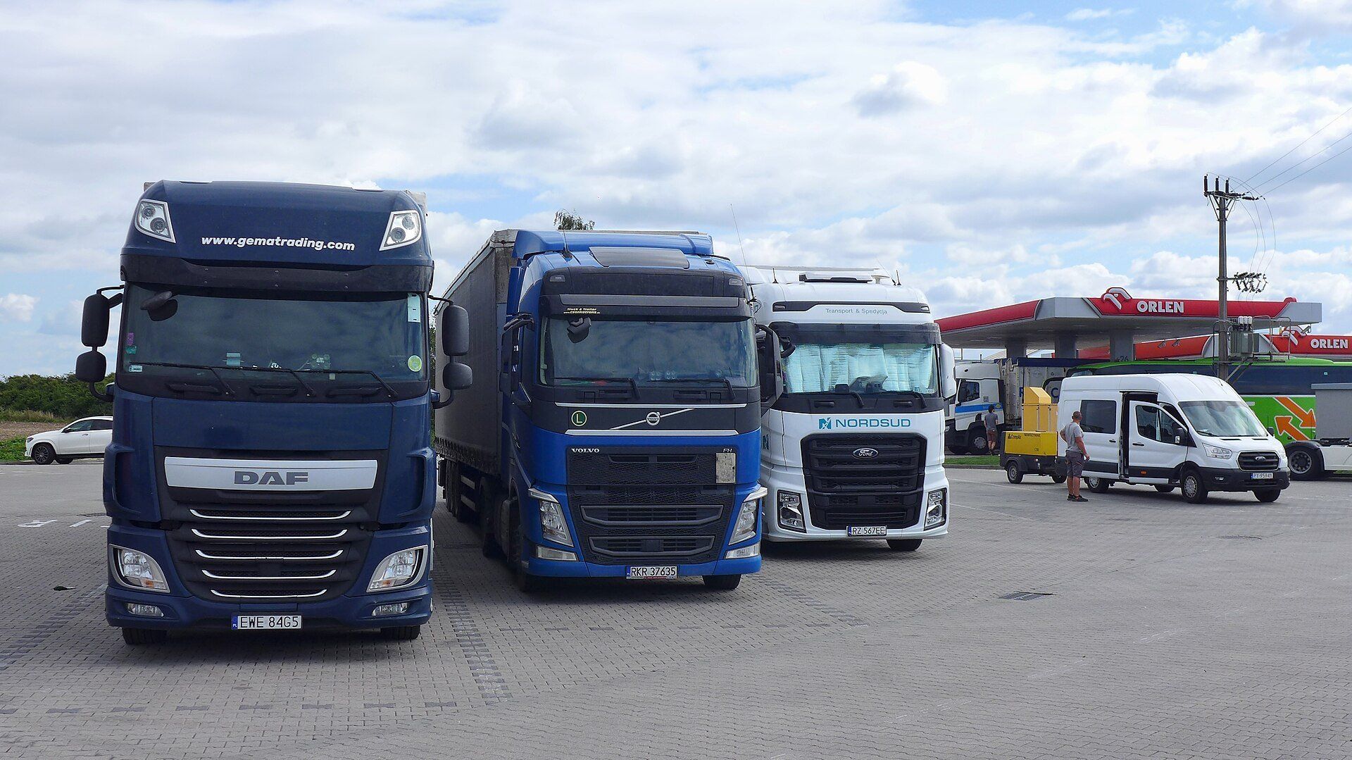 Polonya'da bir Orlen akaryakıt istasyonunun park alanında yan yana duran DAF, Volvo ve Ford F-MAX çekiciler