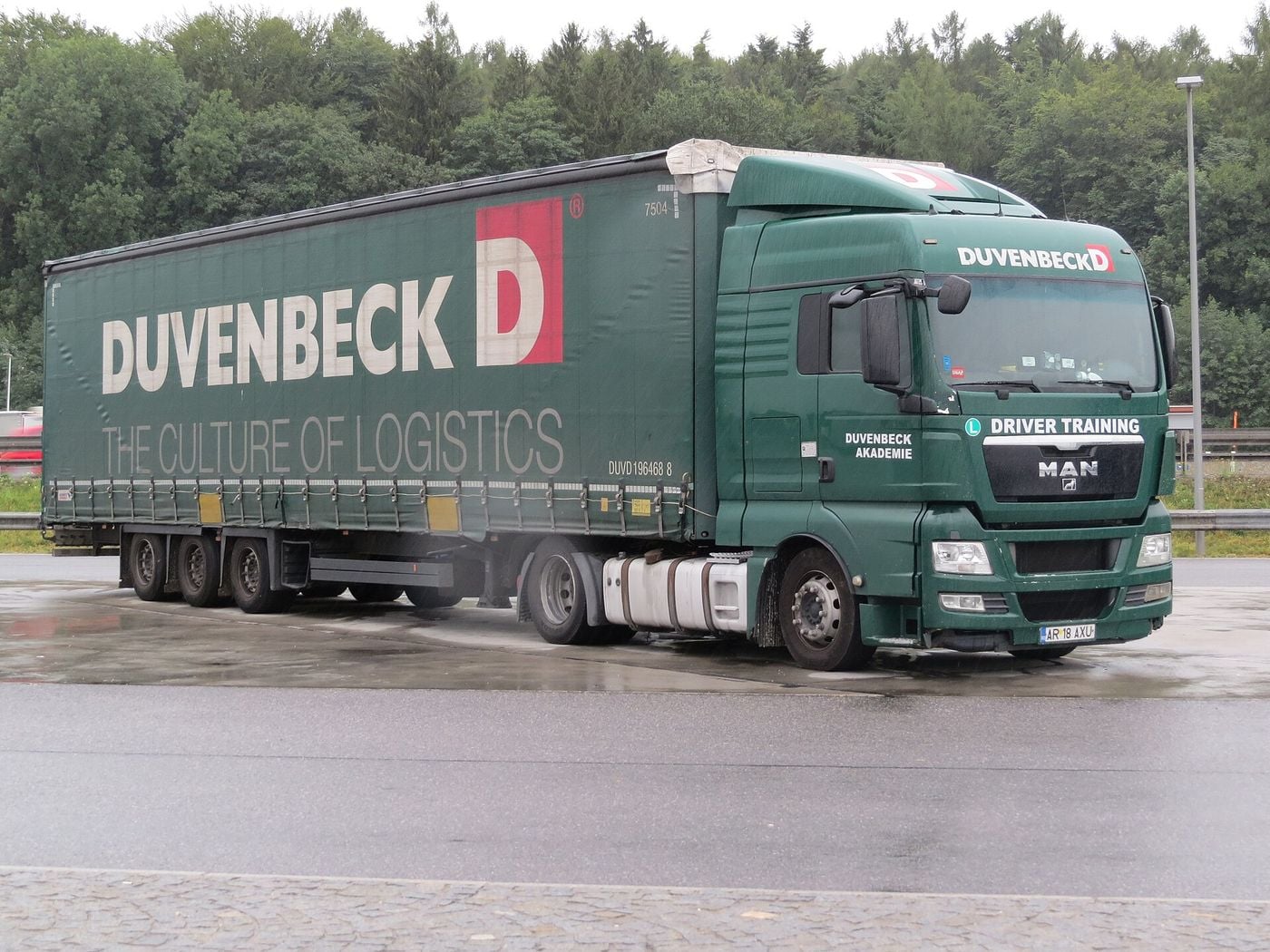 Green MAN tractor unit and three-axle curtainsider semi-trailer marked Driver Training and Duvenbeck Akademie, with an L sign, at the Kirchstetten rest area in Austria