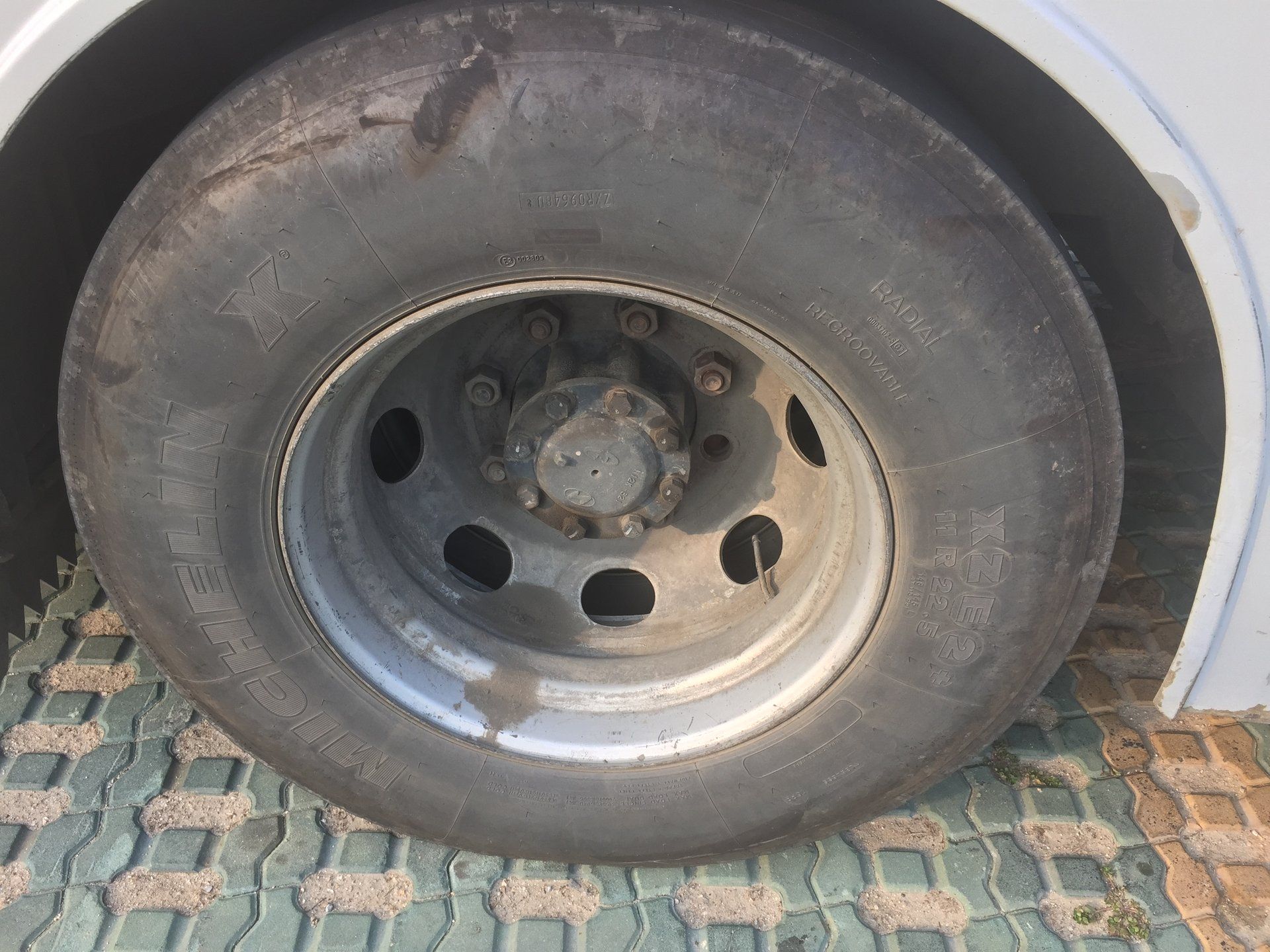 Sidewall of a Michelin XZE2+ tyre on the rear axle of a Hyundai Global 900 bus, with the size 11 R 22.5 and the words RADIAL and REGROOVABLE moulded into the rubber