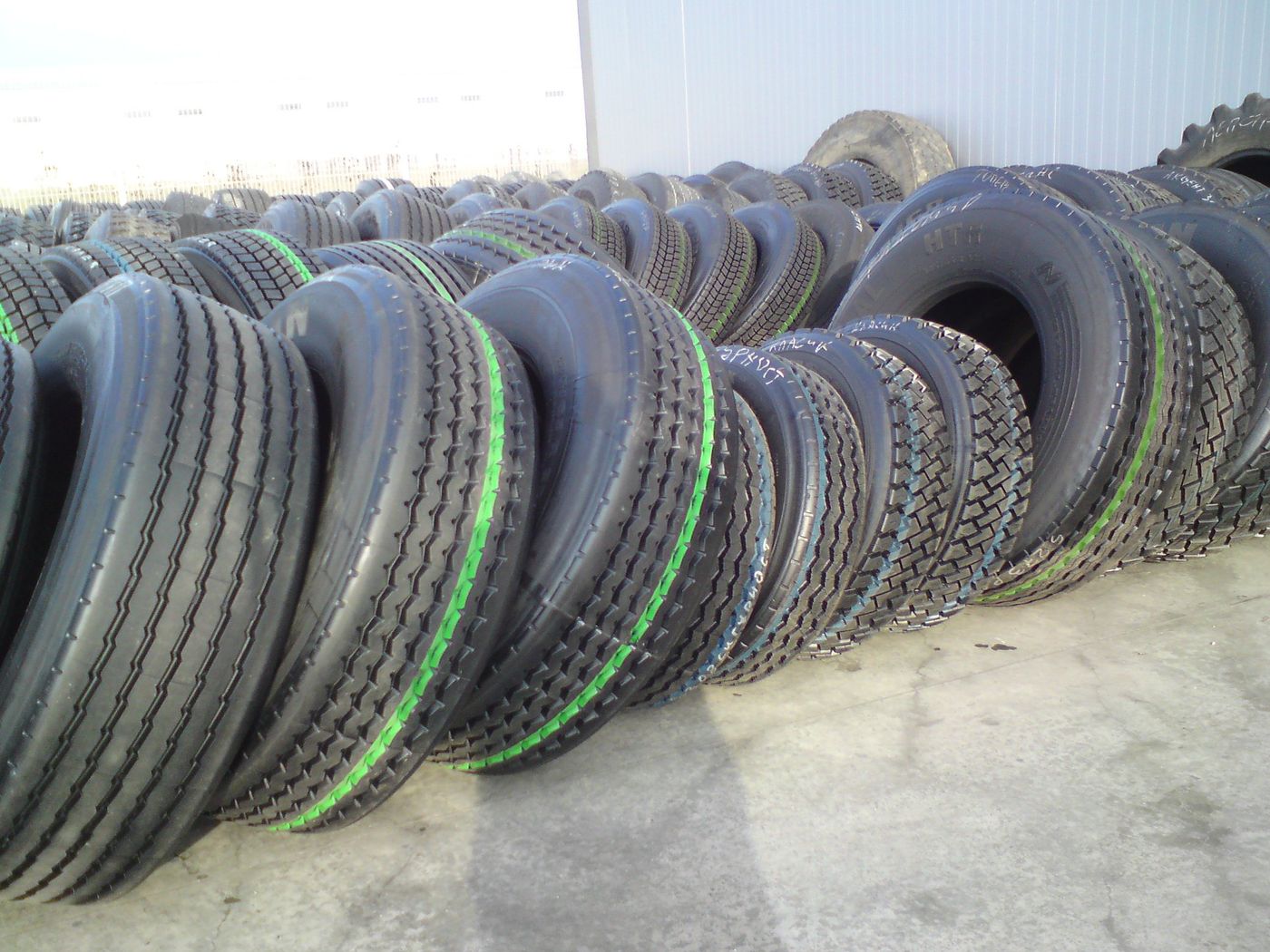 Rows of new truck tyres standing upright in a yard, their tread patterns facing the camera