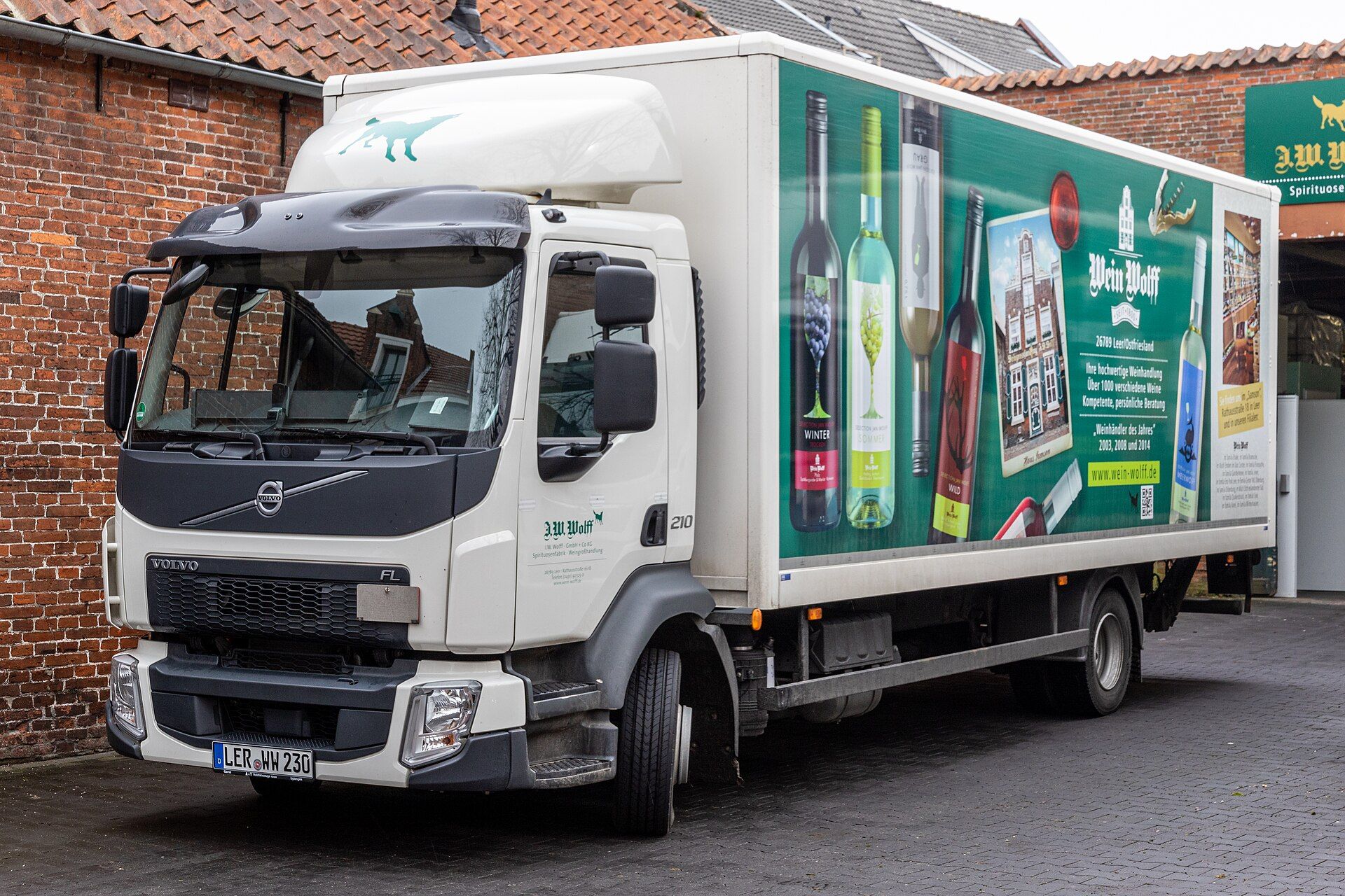 Weißer zweiachsiger Volvo FL 210 mit Kofferaufbau und Ladebordwand, abgestellt auf dem Gelände eines Weinhändlers in Leer, Deutschland