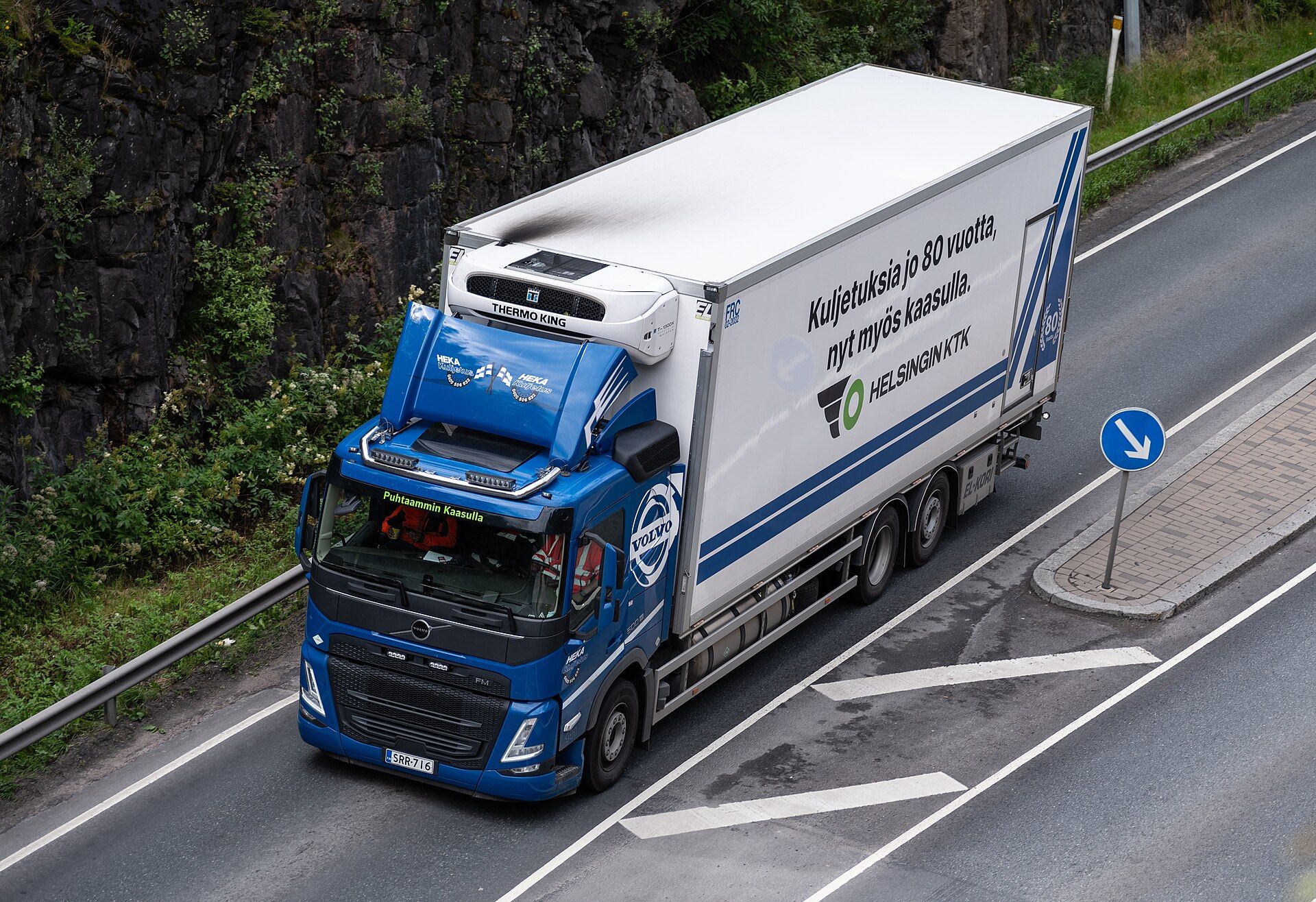 Blue Volvo FM three-axle refrigerated rigid with a Thermo King unit and Finnish lettering about running on gas, on a road in Finland