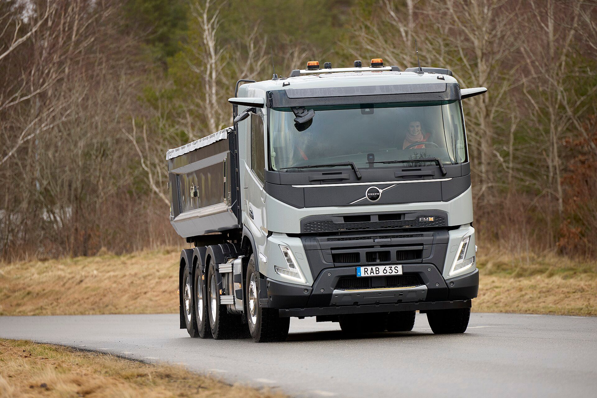 Weißer Volvo FMX, vierachsiger Kipper mit einer gelenkten Einzel-Vorderachse und einer dreiachsigen Hinterachsgruppe, auf einer Landstraße