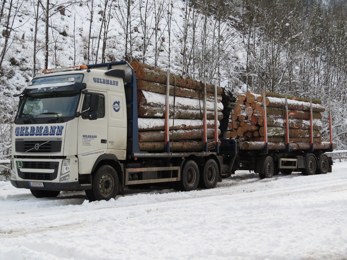 Volvo FH 500 timber truck with a drawbar trailer loaded with logs on a snow-covered road near Frankenfels, Austria, in December 2017