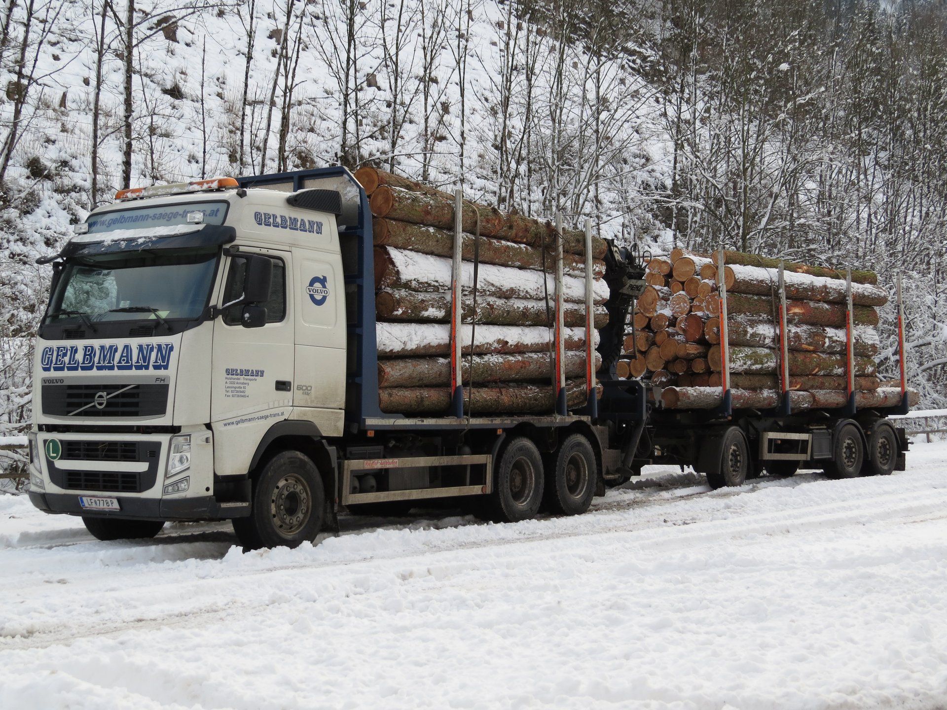 Volvo FH 500 timber truck with a drawbar trailer loaded with logs on a snow-covered road near Frankenfels, Austria, in December 2017